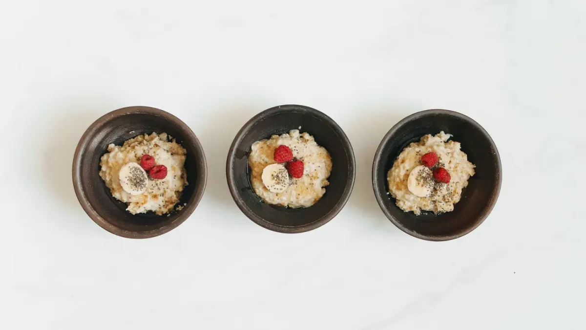 A bowl of plain oatmeal next to a container of dog probiotic soft chews on a kitchen counter