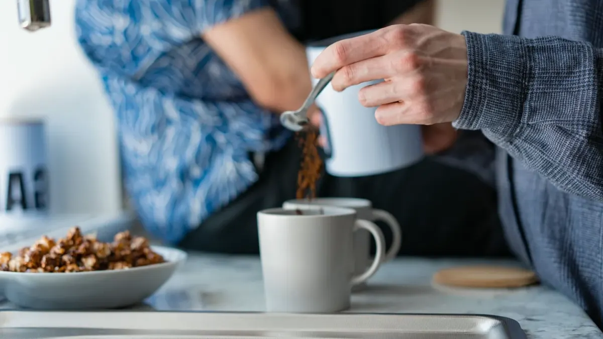 A mug of bone broth beside a stainless steel dog bowl on a kitchen counter