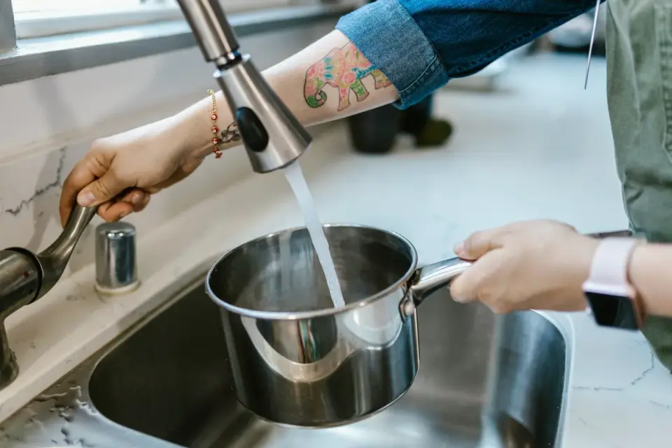 An owner refilling a dog&#x27;s water bowl in a home kitchen